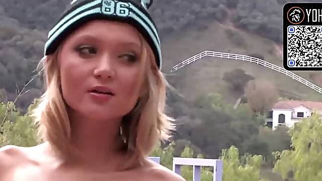 A light-haired teen legal poses in a rosy swimsuit and blue lace undergarments during this behind the scenes