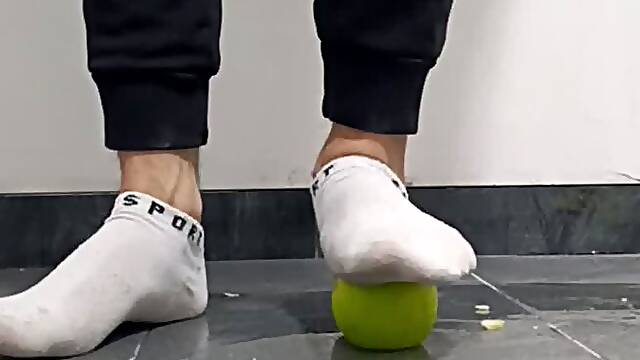 Apples being crushed by male feet in white socks